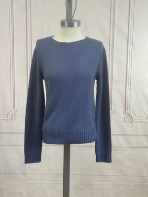 the blue sweater is on a mannequin stand in front of a white wall