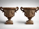 une paire d'urnes en pierre sculptées posées sur des socles, sur fond blanc