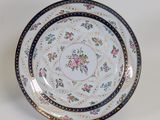 an image of a white plate with a blue border and pink flowers on it