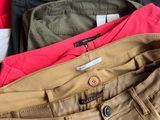 several pairs of pants are stacked on top of each other on a bed