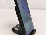 a close up of a cell phone on a stand on a white surface