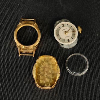 trois montres et une bague posées sur une surface noire