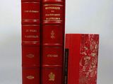 three red books sitting on top of each other on a white surface