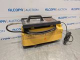 a yellow machine sitting on top of a table next to a wall