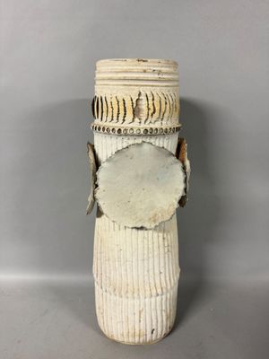a white vase with a wooden handle on a gray surface