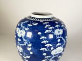 un vase bleu orné de fleurs blanches, posé sur une surface blanche