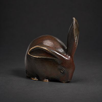 une figurine de lapin marron posée sur une surface noire