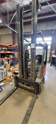 un chariot élévateur dans un entrepôt où il y a beaucoup de cartons par terre