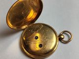 a close up of a gold pocket watch on a white surface