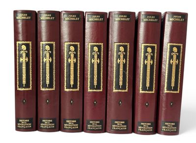 six livres rouges aux tranches dorées sont alignés sur une surface blanche