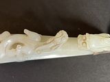 a small carved object on a table next to a metal spoon