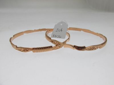deux bracelets rigides en or ornés de motifs gravés sur un fond blanc