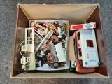 une boîte remplie de jouets, dont un camion de pompiers et un camion de pompiers