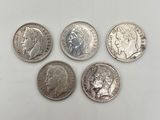 quatre types différents de pièces d'argent sur une surface blanche