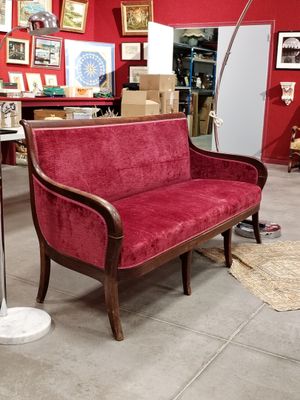 a red couch sitting in a room with pictures on the wall