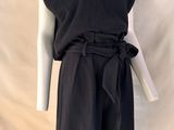 Le mannequin porte une robe noire avec une ceinture.