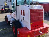 a picture of a red and white tractor parked in front of a building