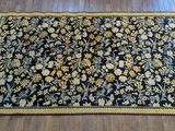 a black rug with yellow and blue flowers on a wooden floor