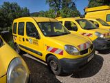 several yellow vans parked in a parking lot with trees in the background
