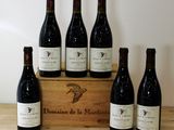 six bottles of wine sit in a wooden box on a table