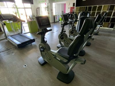 une salle de sport équipée d'une rangée de vélos d'appartement et de tapis de course