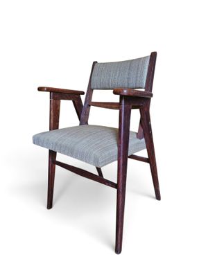 La chaise est en bois et son assise est rembourrée de bleu.