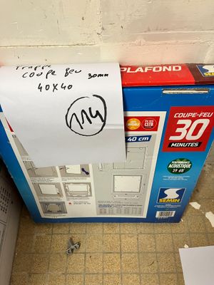 une boîte sur laquelle est posée une pancarte, posée par terre à côté de des toilettes