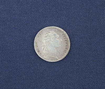 un gros plan d'une pièce d'argent posée sur un tissu bleu