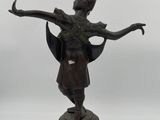 a bronze statue of a woman holding a bird on a pedestal