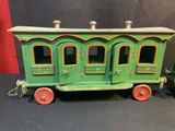 a green toy train with red wheels on a black surface