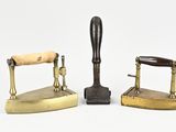three different types of antique brass irons on a white surface