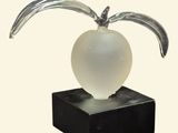 une sculpture en verre représentant une pomme posée sur un socle noir