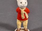 a figurine of a cat wearing a red shirt and yellow pants