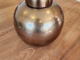 un vase en or posé sur une table en bois dans un salon