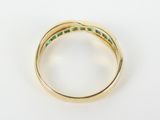 a close up of a gold ring with emerald stones