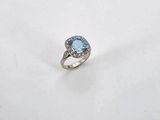 an oval blue topaze and diamond ring on a white surface
