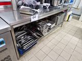 un plan de travail en acier inoxydable sur lequel sont posés des casseroles et des poêles, dans une cuisine professionnelle