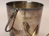 a silver bucket with a spoon and spoon rest next to it