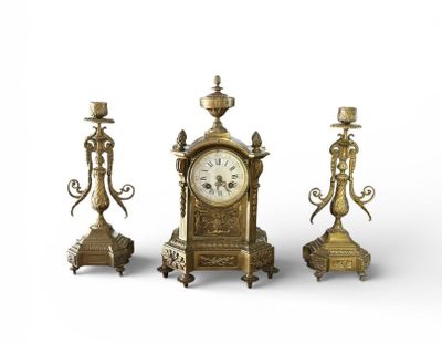 three brass candlesticks and a clock on a white background