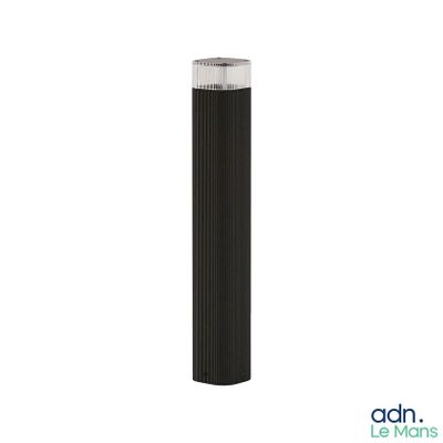 the black cylinder lamp is next to a white wall