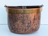an old copper pot with a handle on a white surface