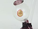 a small glass vase with a red handle on a stand