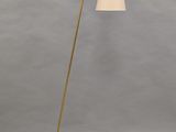 a brass floor lamp with a white shade on top of it