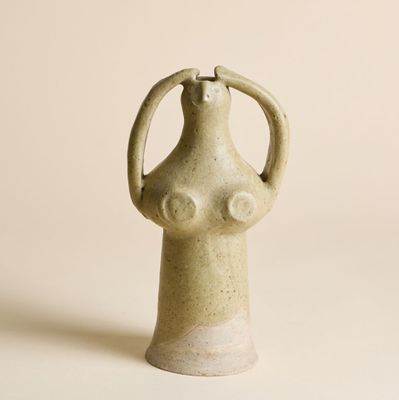 vase en céramique beige posé sur une surface blanche, sur fond blanc