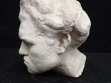 plaster bust of a man ' s head on a black background