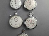 four stopwatchs on a gray surface with a clock in the middle