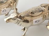 two silver cow figurines with numbers on them