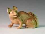 une figurine représentant un chat assis sur une surface blanche