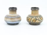 two small vases sitting side by side on a white surface