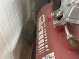 a red air compressor sitting on the floor next to a wall